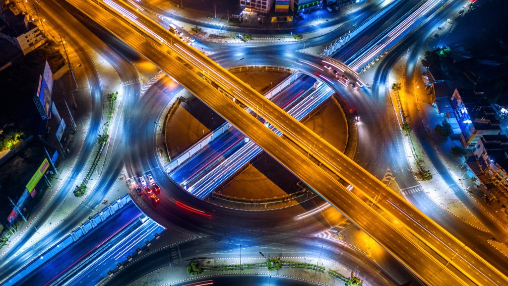 Aerial view of traffic in roundabout and highway at night.